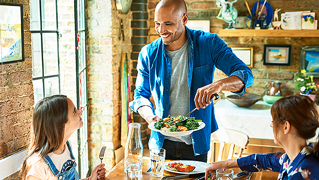 A man serving his family dinner